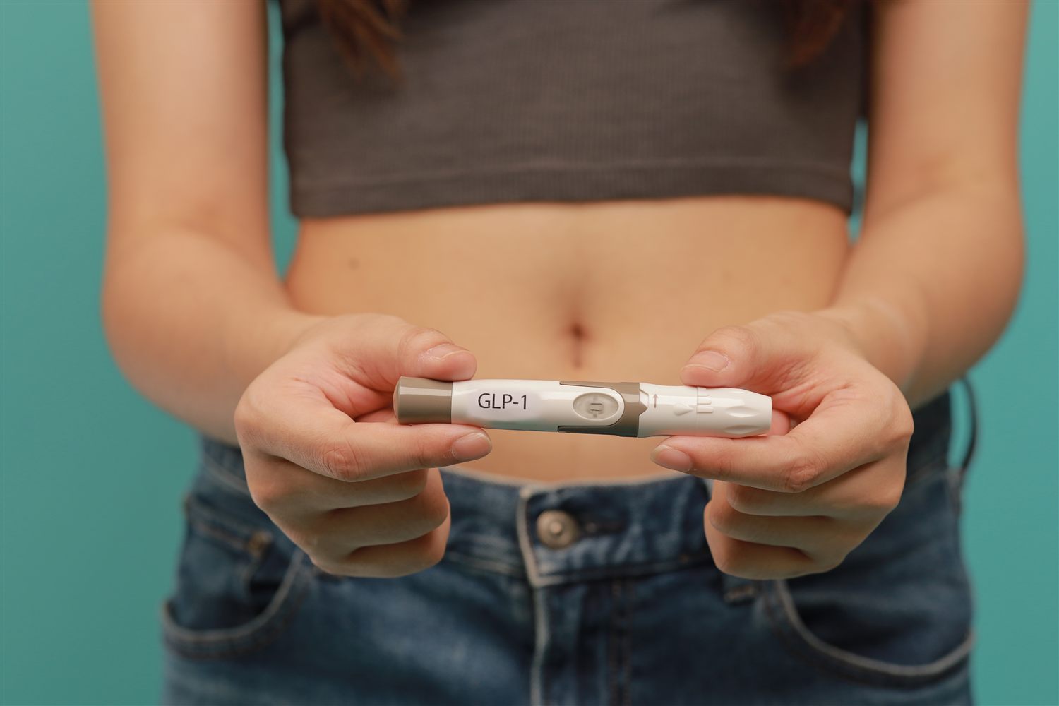 A person holding a GLP-1 medication injector pen