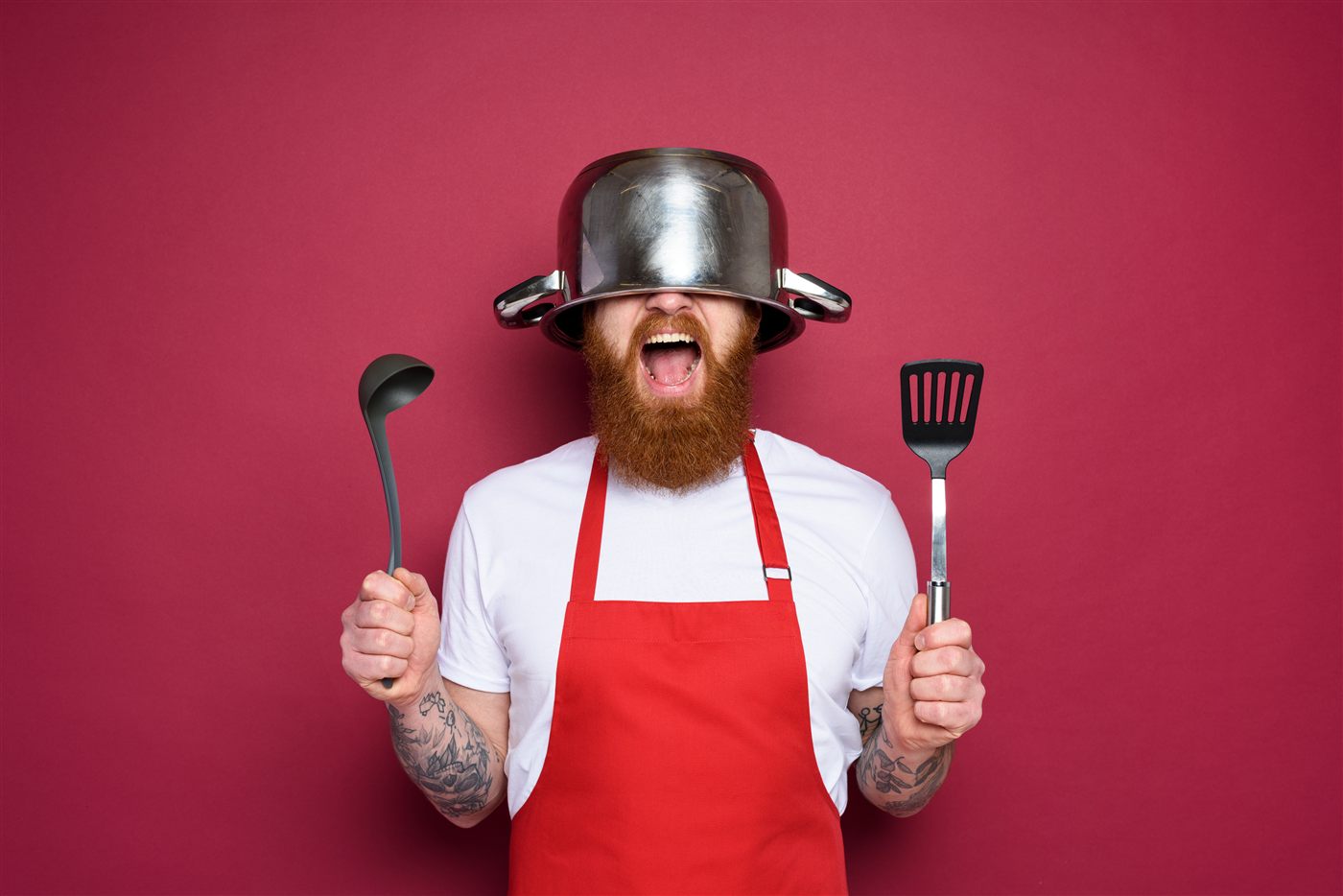 Home cook wearing an apron holding a ladle and spatula